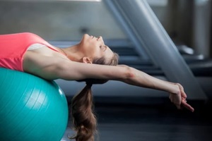 woman exercising her abs on ball pilates ball in gym