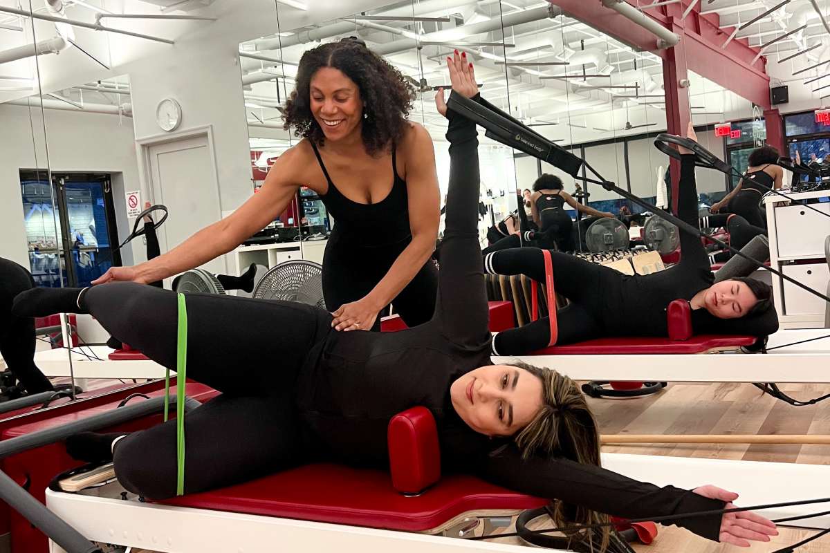 Potomac MD Pilates Instructor assisting beginner pilates student on reformer