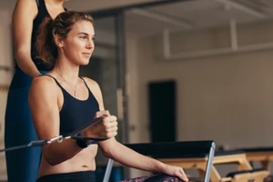 woman at a pilates gym pulling stretch bands