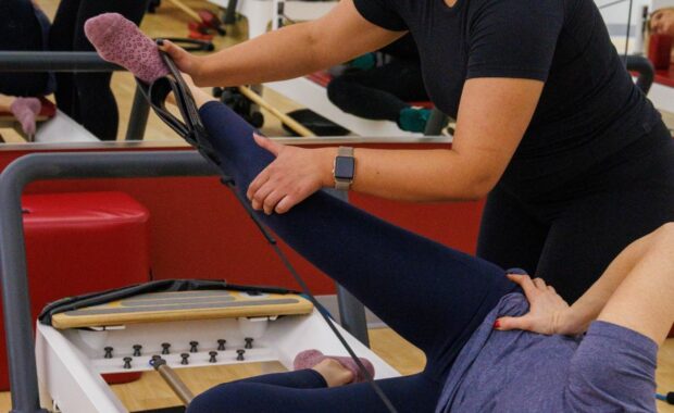 Potomac MD Pilates Instructor assisting client with reformer exercises