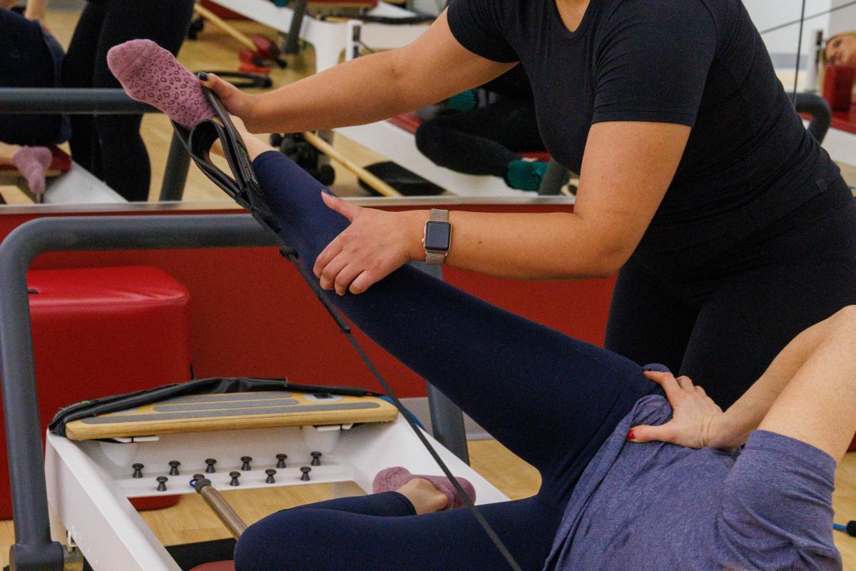 Potomac MD Pilates Instructor assisting client with reformer exercises