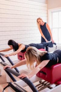 Pilates instructor correct reformer plank in DC pilates class