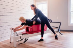 DC reformer pilates instructor corrects positioning