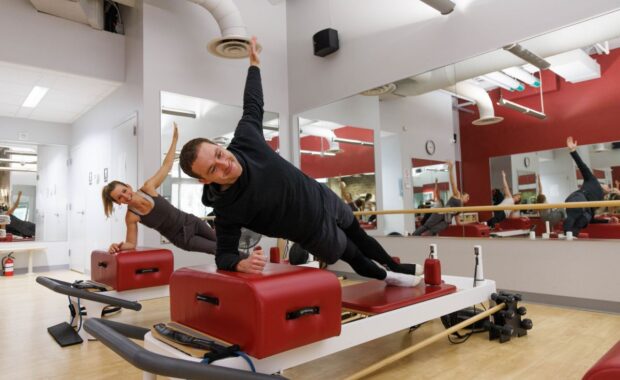 DC man doing side plank on reformer pilates