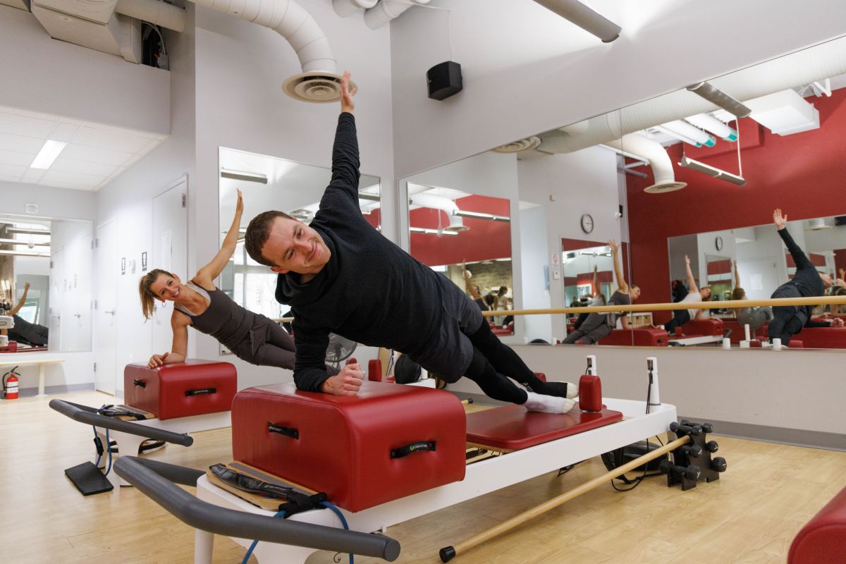 DC man doing side plank on reformer pilates