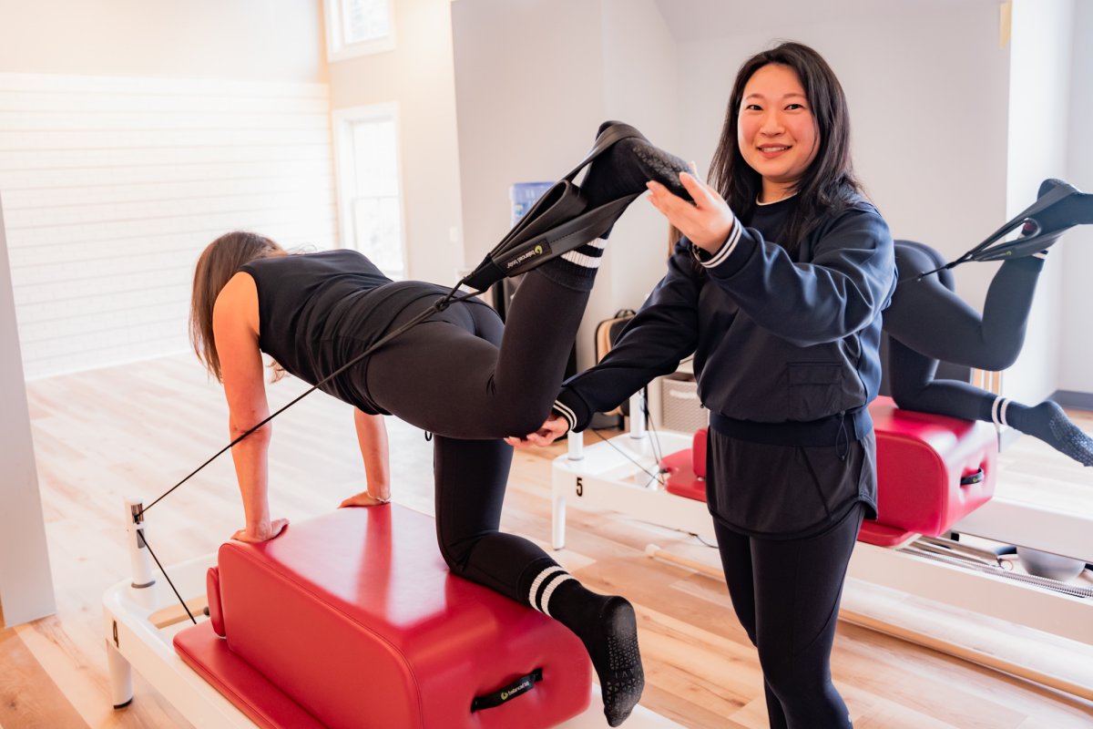 Christine, Chevy Chase, VA pilates instructor, holding foot in strap on pilates reformer