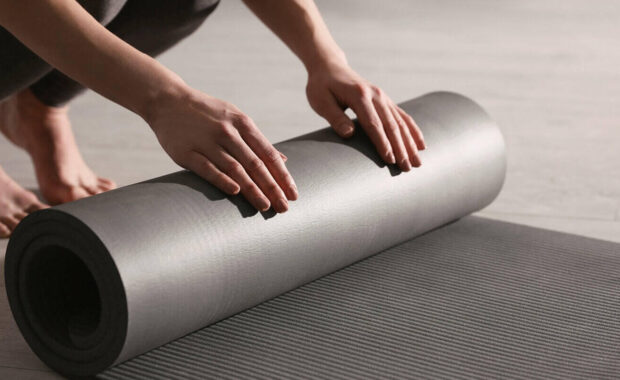 woman rolling yoga mat in studio