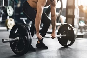 muscular powerlifter lifting heavy barbell from gym floor