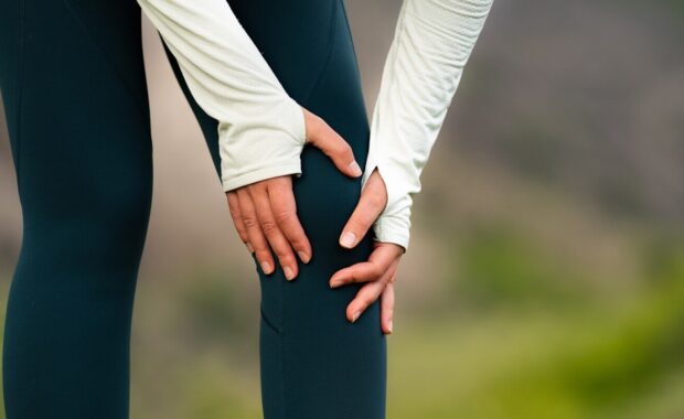 woman holding knee in pain after outdoor workout