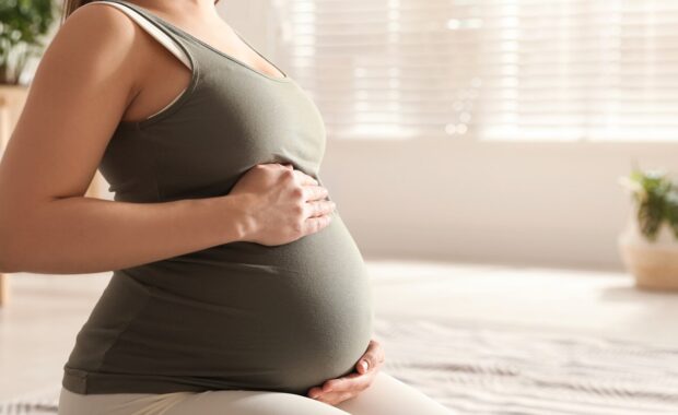 young pregnant woman practicing reformer pilates at home in Friendship Heights, MD